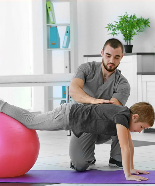 A Boy Getting Physiotherapy With Pink Ball From His Therapist