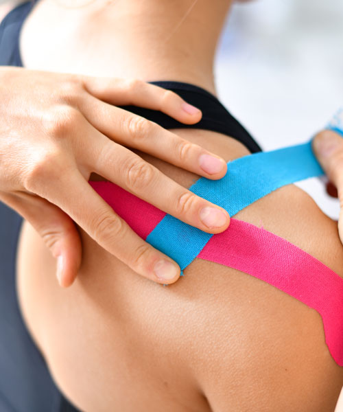 A Therapist Applying Kinesio Tape On Patient's Shoulder